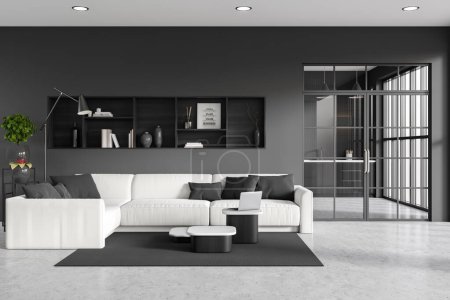 Photo for Dark studio interior with sofa, coffee table with laptop and shelf with decor. Cooking area with kitchenware behind glass doors. Panoramic window. 3D rendering - Royalty Free Image
