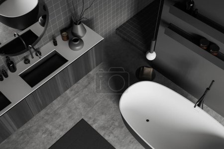 Photo for Top view of dark bathroom interior with sink and bathtub. Black wooden dresser and shelf with bathing accessories, grey concrete floor. 3D rendering - Royalty Free Image