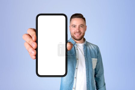 Photo for Happy man portrait showing a big smartphone mock up empty screen, blue background. Concept of social media, mobile app and online communication - Royalty Free Image