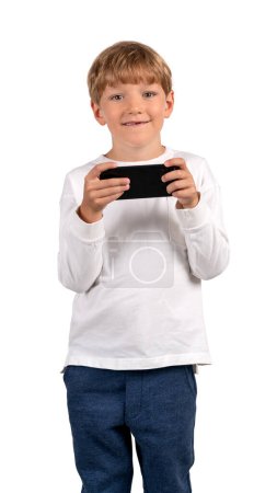 Téléchargez les photos : Happy child boy with smartphone in hands, portrait looking at the camera, isolated over white background. Concept of online games and social media - en image libre de droit