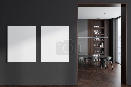 Téléchargez les photos : Dark living room interior with dining table on hardwood floor. Shelf with decoration and panoramic window on skyscrapers. Two mock up posters on partition. 3D rendering - en image libre de droit