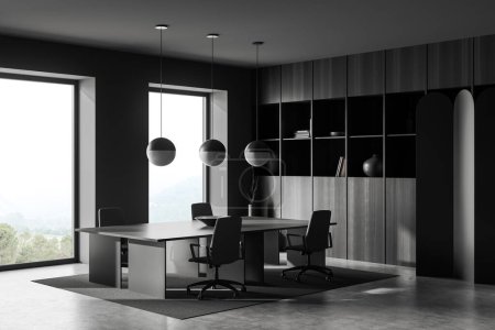 Téléchargez les photos : Dark office interior with armchairs and desk on carpet, grey concrete floor. Black wooden shelf with books and panoramic window on countryside. 3D rendering - en image libre de droit