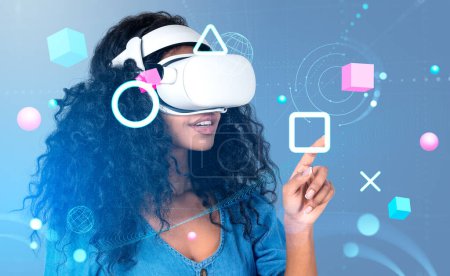 Foto de African American businesswoman wearing formal wear and vr headset touching metaverse reality with blockchain system. Blue background, spheres. Concept of modern technology and playing virtual game - Imagen libre de derechos