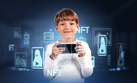 Foto de Smiling handsome boy in casual wear standing holding smartphone with digital interface with nft tokens and pictures. Concept of ambitious child, kid, young collector, gallery exhibition of virtual art - Imagen libre de derechos