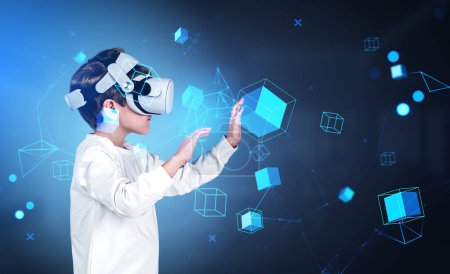 Téléchargez les photos : Boy wearing casual wear and vr headset touching metaverse reality with blockchain system. Dark blue background. Concept of futuristic technology, virtual reality and progressive kids in business - en image libre de droit