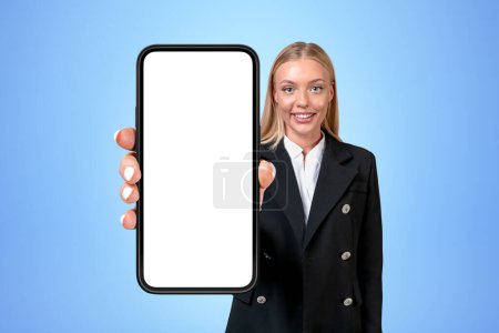 Foto de Happy businesswoman showing phone with big mock up copy space screen, blue background. Concept of website and social media - Imagen libre de derechos