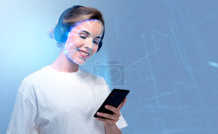 Téléchargez les photos : Smiling businesswoman wearing headphones typing on smartphone with facial recognition by digital interface with line connection hologram. Concept of modern technology of artificial intelligence - en image libre de droit