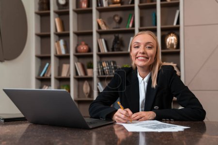 Foto de Happy businesswoman sign a contract, laptop on desk and shelf with decoration. Concept of startup, recruitment and future career. - Imagen libre de derechos