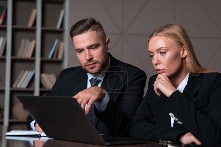 Photo for Businesswoman and businessman wearing formal wear sitting working on laptop at office workplace in background. Concept of teamwork, work together, business people, coworking, cooperation - Royalty Free Image