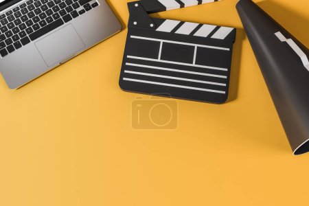 Foto de Computer and clapper with megaphone on yellow background. Concept of online cinema. Mockup copy space, 3D rendering - Imagen libre de derechos