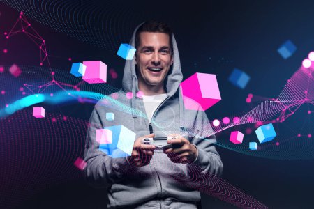 Foto de Happy man in a hood with a gamepad in hands, playing in virtual reality. Metaverse and information fields with data blocks floating. Concept of cyberspace and technology - Imagen libre de derechos