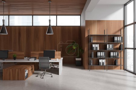 Photo for Wooden business interior with coworking area and shelf with folders, pc computer on desk, grey concrete floor. Panoramic window on skyscrapers. 3D rendering - Royalty Free Image