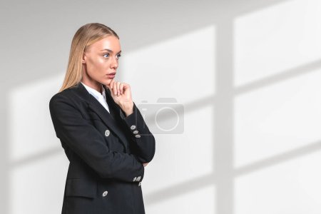 Téléchargez les photos : Businesswoman in black formal suit standing with thoughtful look, copy space white background. Manager making up plans and new ideas. Concept of startup - en image libre de droit