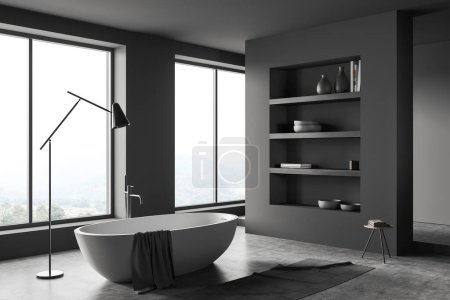 Téléchargez les photos : Dark bathroom interior with bathtub, shelf with decoration, side view, carpet on grey concrete floor. Panoramic window on countryside. Washing room in hotel apartment. 3D rendering - en image libre de droit