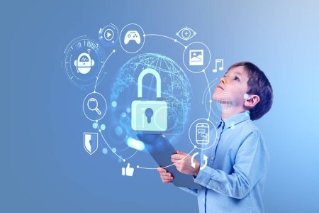 Téléchargez les photos : Enfant garçon avec tablette regardant l'hologramme de hud de cybersécurité, grand cadenas et sphère terrestre. Icônes Web et connexion globale. Concept de protection des données - en image libre de droit