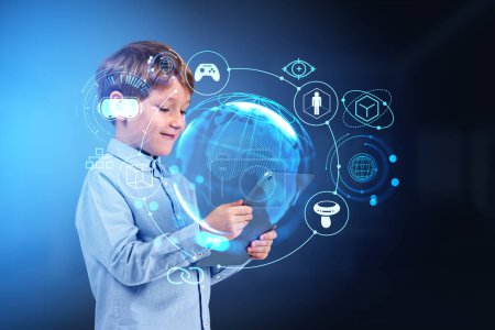 Foto de Niño niño usando tableta, holograma metaverso con diferentes iconos brillantes, realidad virtual y conexión mundial. Concepto de educación en línea y juegos - Imagen libre de derechos