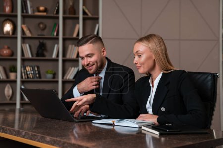 Photo for Happy businessman and businesswoman working together, woman finger pointing at laptop screen surprised. Concept of teamwork and success - Royalty Free Image