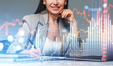 Foto de Businesswoman smiling, sign a contract, laptop on office desk. Stock market changes, forex candlesticks, virtual screen hud with chart and lines. Concept of investment - Imagen libre de derechos