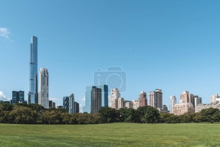 Foto de Rascacielos de Nueva York, césped verde en el parque central con árboles. Skyline de megápolis y centro de comercio financiero. Concepto de negocio y estilo de vida - Imagen libre de derechos