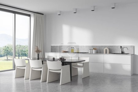 Foto de White kitchen interior with chairs and dining table, side view, light concrete floor. Cooking space with kitchenware and panoramic window on countryside, 3D rendering - Imagen libre de derechos