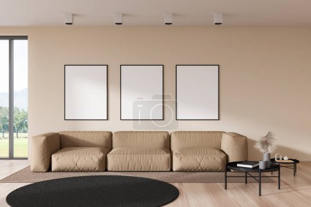 Foto de Light living room interior with sofa and coffee table, carpet on hardwood floor. Lounge zone and three mockup posters in row on beige wall. 3D rendering - Imagen libre de derechos