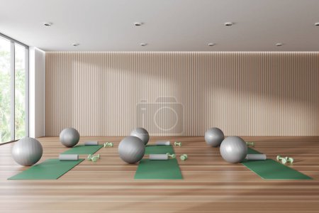 Téléchargez les photos : Beige sport class interior with mat and fitball on hardwood floor. Fitness room with equipment and panoramic window on tropics view. 3D rendering - en image libre de droit