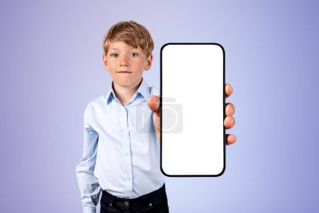 Foto de Child boy showing a smartphone with copy space mock up screen, purple background. Concept of online learning and mobile app - Imagen libre de derechos