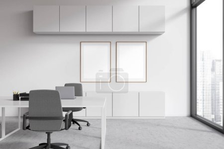 Photo for White workspace interior with laptop on desk, grey concrete floor. Business room with shelves and panoramic window on skyscrapers. Two mockup canvas posters. 3D rendering - Royalty Free Image