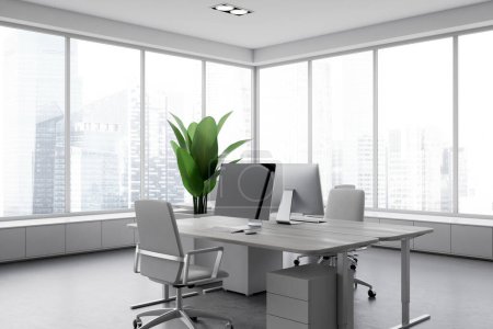 Foto de Interior de la oficina blanca con ordenador PC en el escritorio, vista lateral piso de hormigón gris. Rincón de coworking con mobiliario moderno y ventana panorámica sobre rascacielos. Renderizado 3D - Imagen libre de derechos