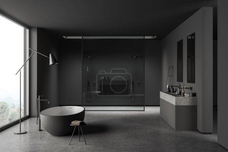 Téléchargez les photos : Dark bathroom interior with bathtub, sink and shower behind glass partition, grey concrete floor. Modern hotel studio with panoramic window on countryside. 3D rendering - en image libre de droit