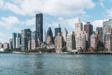 Téléchargez les photos : New York Midtown sous un ciel clair, front de mer et nuages. Immeubles de bureaux à Manhattan, gratte-ciel côté est et skyline, entreprise - en image libre de droit