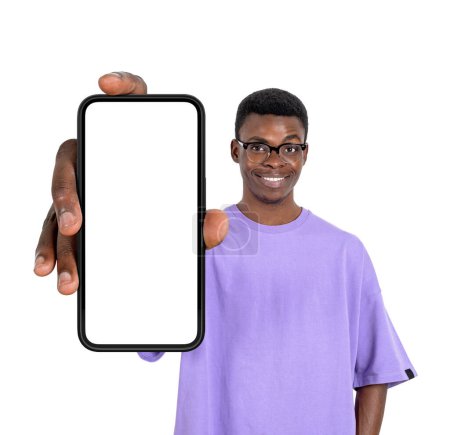 Téléchargez les photos : Jeune homme africain en lunettes souriant, montrant smartphone maquette écran d'espace de copie, isolé sur fond blanc. Concept de nouveau site web et médias sociaux - en image libre de droit