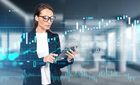 Foto de Businesswoman in eyeglasses working with tablet in hands. Virtual screen with bar chart, forex diagrams hud, office room on background. Concept of trading and analysis - Imagen libre de derechos