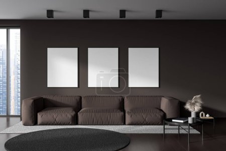 Photo for Dark living room interior with sofa and coffee table, carpet on hardwood floor. Chill space and three mockup posters in row on brown wall. 3D rendering - Royalty Free Image