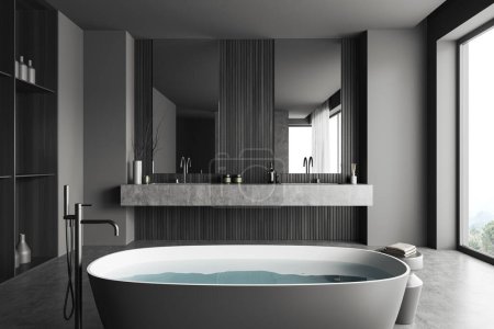 Téléchargez les photos : Intérieur salle de bain sombre avec baignoire et eau, double lavabo avec accessoires et sol en béton gris. Fenêtre panoramique sur campagne. rendu 3D - en image libre de droit