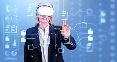 Téléchargez les photos : Businesswoman wearing vr headset is watching at metaverse reality with document management system. Blue background. Concept of modern technology and information documentation database - en image libre de droit