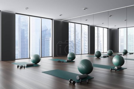 Téléchargez les photos : Dark modern sport class interior with yoga mat and fitball, side view on hardwood floor. Fitness room corner with large mirror and panoramic window on skyscrapers. 3D rendering - en image libre de droit