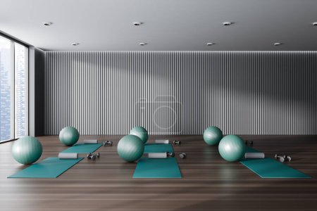 Téléchargez les photos : Dark minimalist yoga gym interior with mat and fitball on hardwood floor. Fitness center with equipment and panoramic window on city view. 3D rendering - en image libre de droit