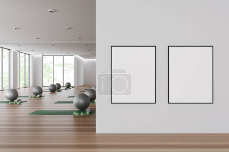 Photo for White sport class interior with mat and fitball on hardwood floor. Yoga room with equipment and panoramic window on tropics. Two mock up posters on partition. 3D rendering - Royalty Free Image