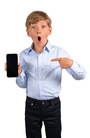 Photo for Child boy with open mouth pointing at phone in hand, surprised look. Isolated over white background. Concept of idea and mobile app - Royalty Free Image