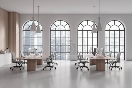 Photo for Interior of stylish open space office with white and wooden walls, concrete floor, long wooden computer tables, white file cabinet and arched windows with blurry cityscape. 3d rendering - Royalty Free Image