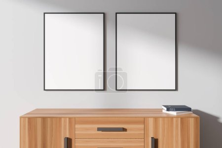 Téléchargez les photos : Deux maquettes verticales de cadres d'affiche suspendus sur un mur blanc au-dessus d'armoire en bois clair avec des livres. Concept de publicité. Rendu 3d - en image libre de droit
