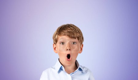 Téléchargez les photos : Portrait d'un petit garçon étonné sur fond de mur violet. Concept d'émotions, de surprise et d'éducation. Pensée et planification, bonne idée - en image libre de droit
