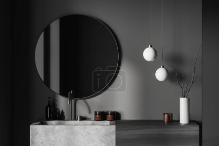 Téléchargez les photos : Intérieur salle de bain sombre avec lavabo et miroir rond, lavabo en béton gris et accessoires de bain, bouteille de savon et vase. rendu 3D - en image libre de droit