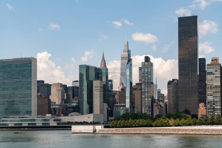 Téléchargez les photos : Siège des Nations Unies. New York Midtown sous un ciel clair, front de mer et nuages. Immeubles de bureaux à Manhattan, East River et gratte-ciel skyline. - en image libre de droit