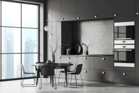 Photo for Corner of stylish kitchen with gray and mosaic walls, concrete floor, dark gray cupboards and cabinets and round table with chairs. Window with blurry cityscape. 3d rendering - Royalty Free Image