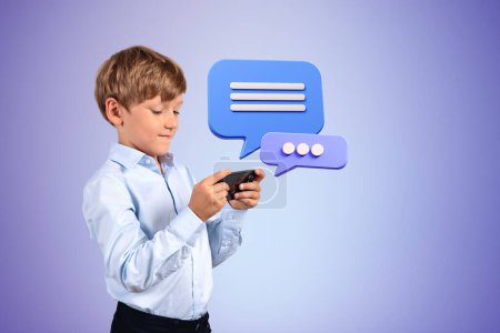 Téléchargez les photos : Portrait d'un petit garçon sérieux utilisant un smartphone sur fond violet avec des bulles d'expression. Concept de médias sociaux et de messagerie. Maquette - en image libre de droit