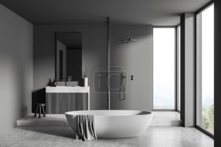Téléchargez les photos : Intérieur salle de bain sombre avec baignoire au sol en béton gris. Évier avec miroir, douche et terrasse avec accessoires, fenêtre panoramique sur la campagne. rendu 3D - en image libre de droit