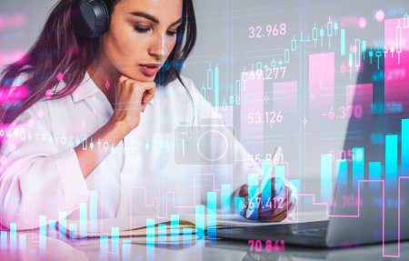 Photo for Businesswoman with pen in hand, listening to financial podcast. Double exposure with colorful bar chart and candlesticks, forex diagrams. Concept of education - Royalty Free Image