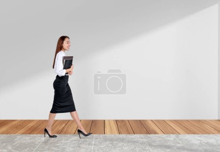 Téléchargez les photos : Femme d'affaires marchant avec des contrats d'affaires dans les mains, souriant et regard heureux, carrelage et plancher de bois franc. Concept de réussite et de progrès. Espace de copie - en image libre de droit